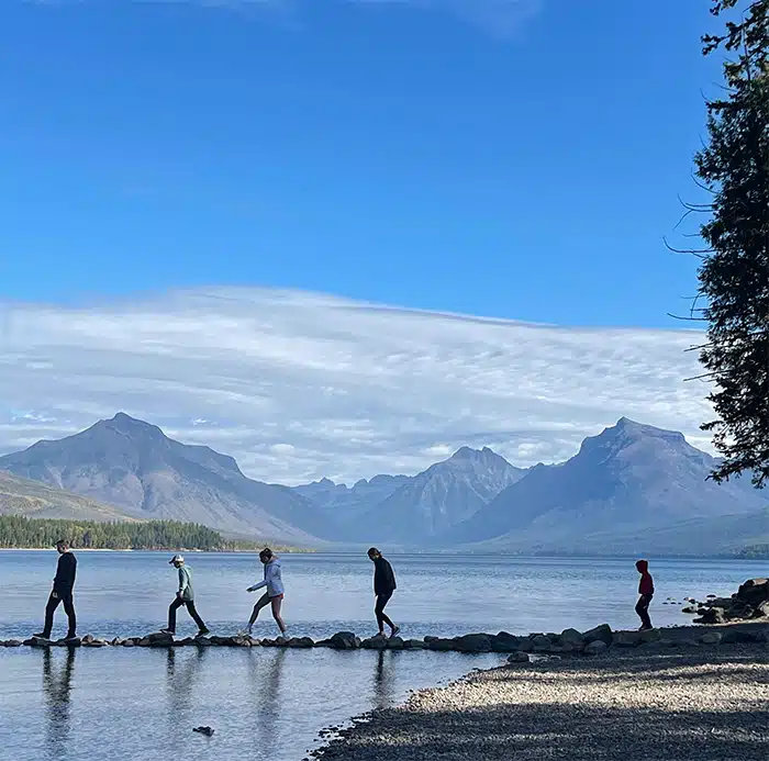 People walking at Lake McDonald in Glacier National Park with blue sky