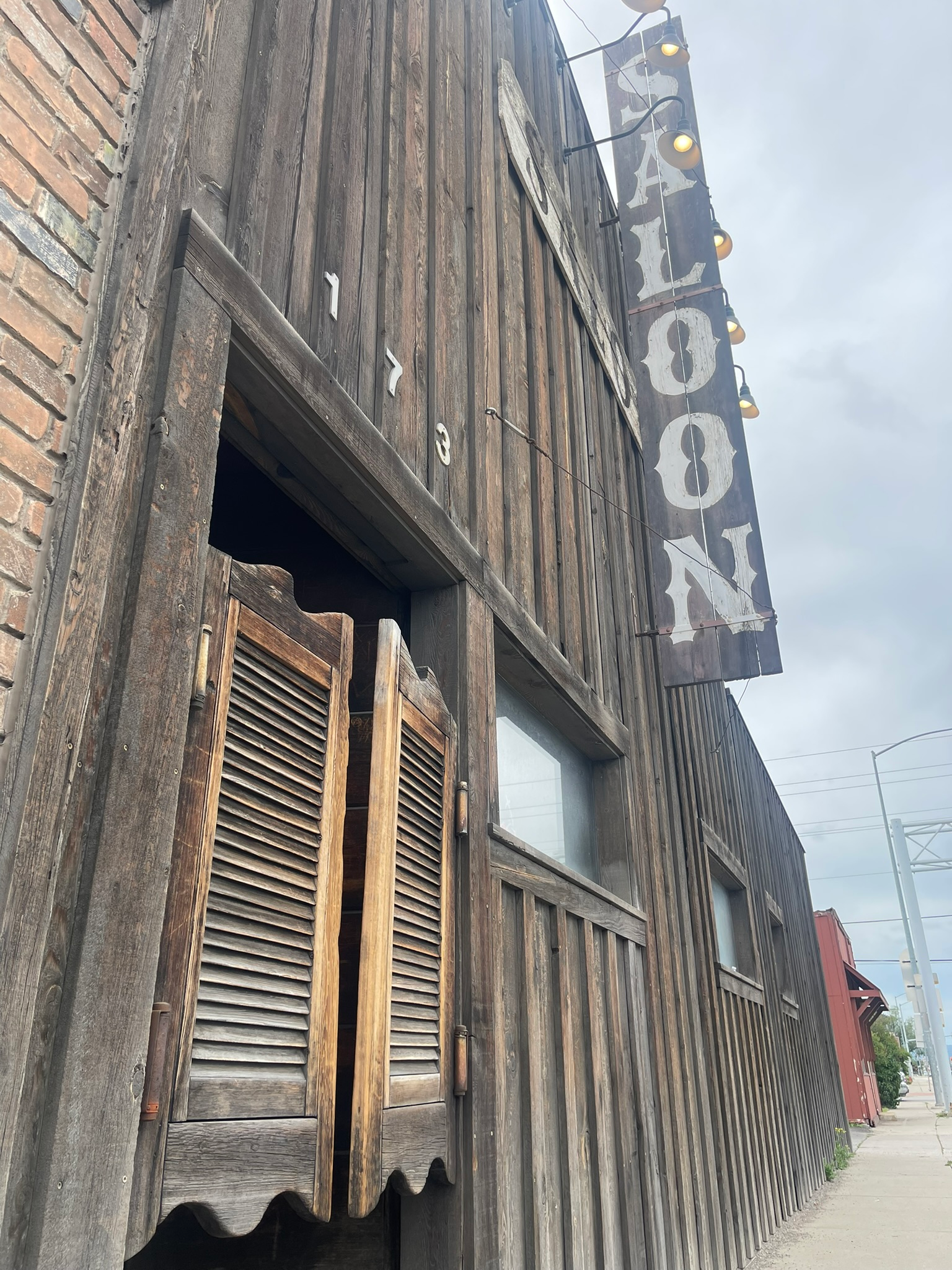 Exterior of Moose's Pizza with swinging wooden doors and a saloon sign, Best Pizza in Kalispell: Moose's