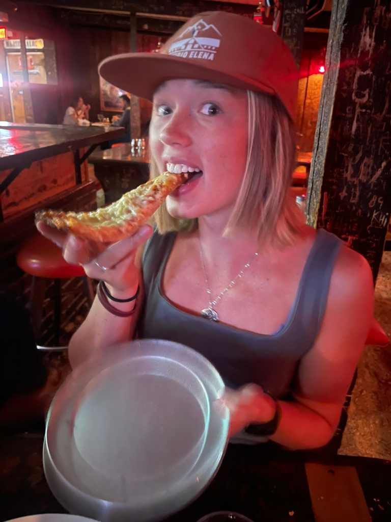 Young woman eating sausage and sauerkraut pizza at Moose's Saloon and Pizza in Kalispell, MT
