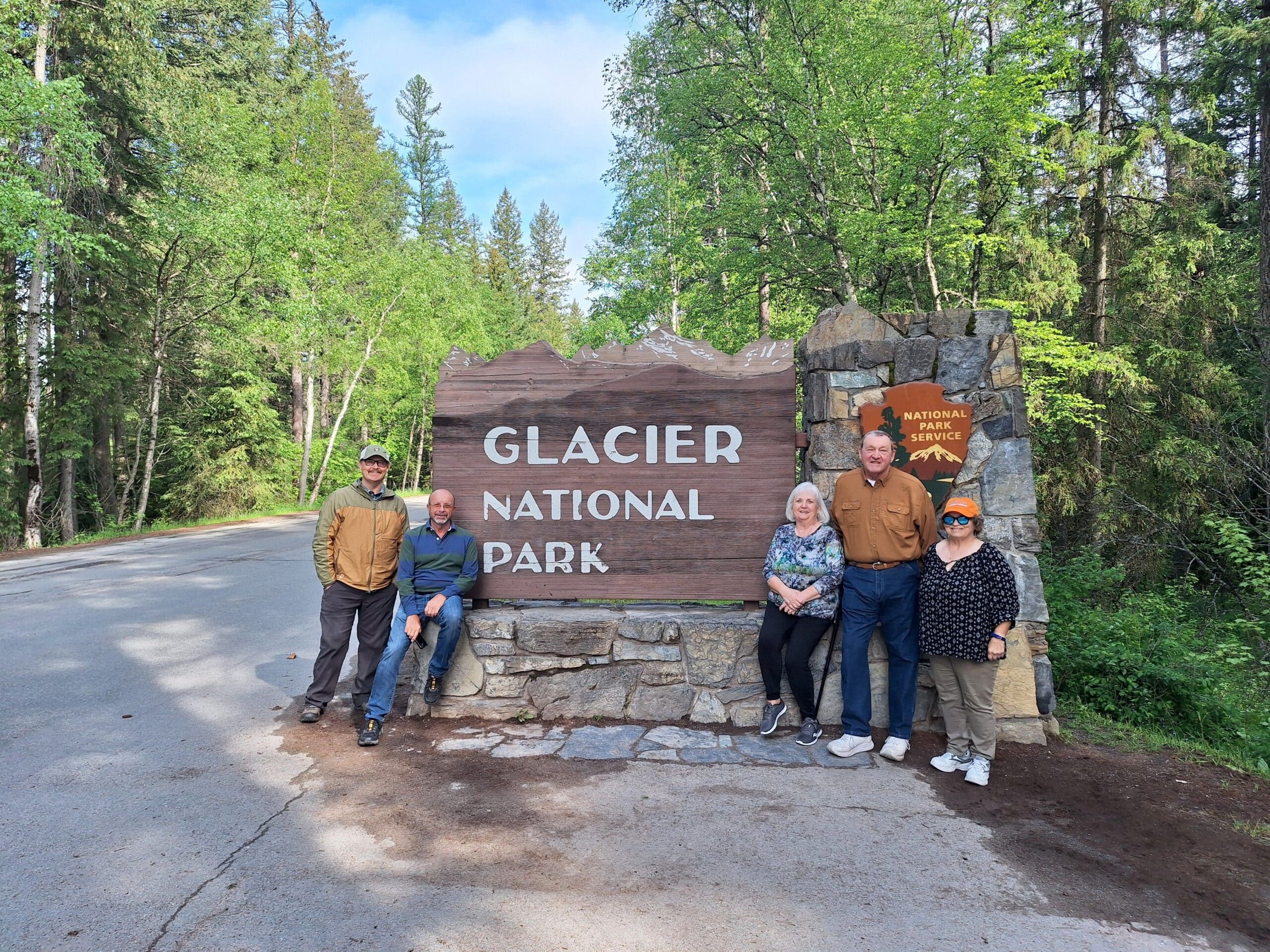Family poses by Glacier National Park Sign