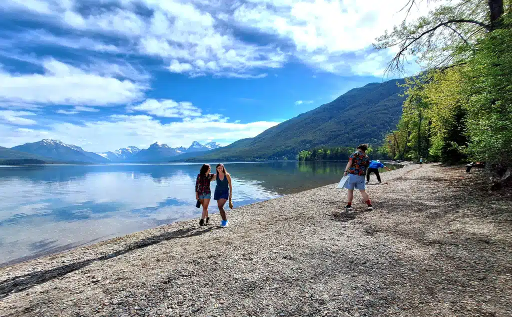 Tour guests of Tour Glacier skip rocks on the shore of Lake McDonald
