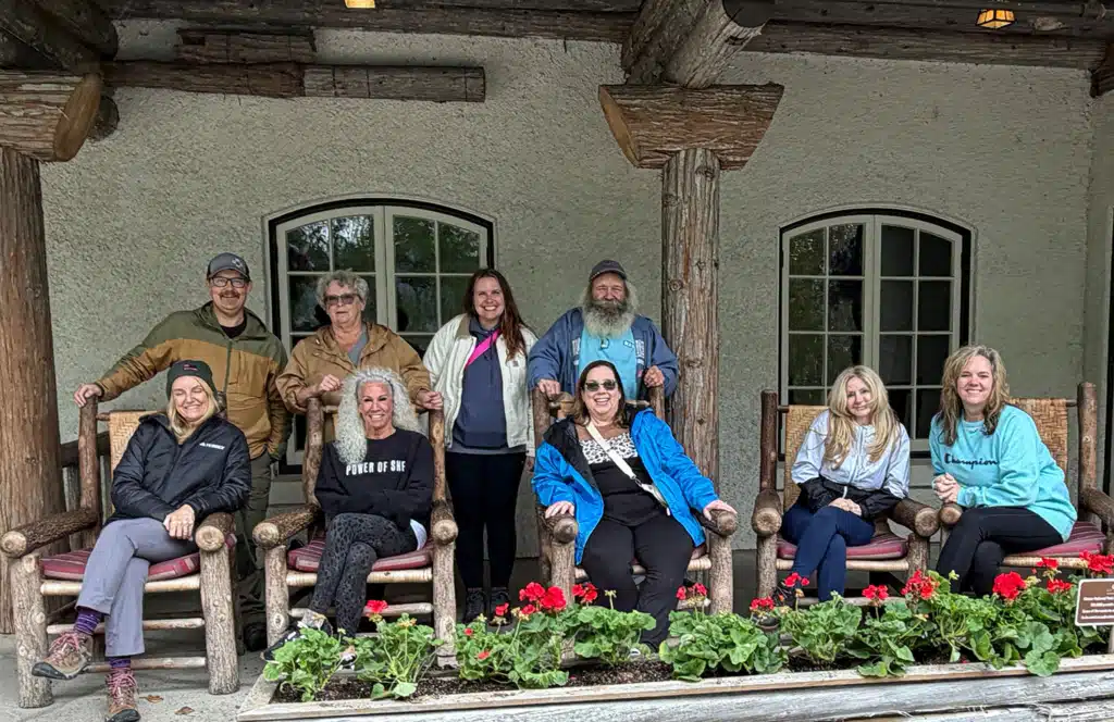 8 people sitting on the porch of Lake McDonald Lodge