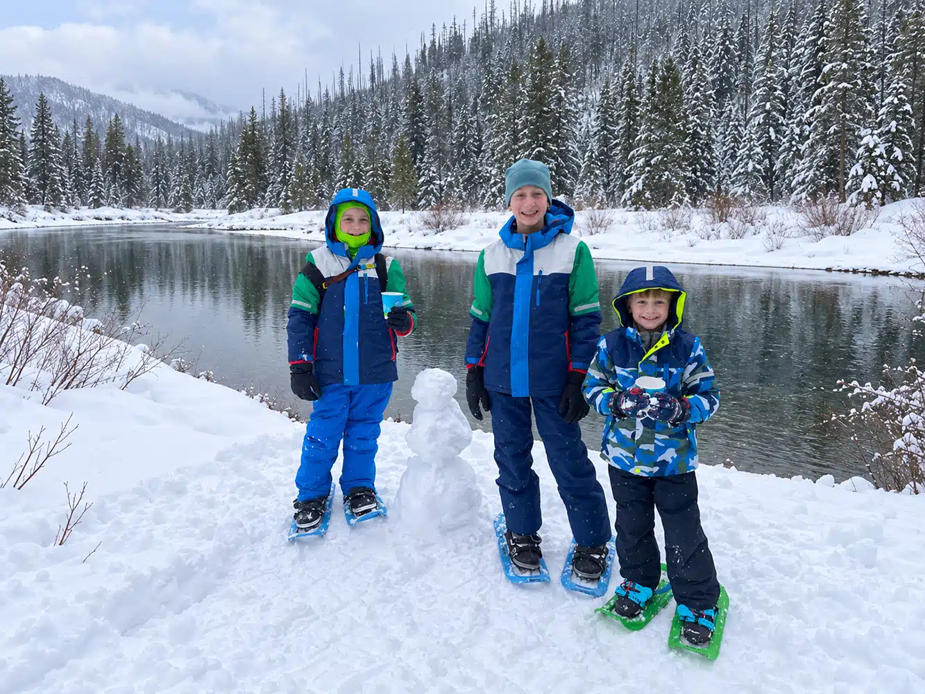 Children with a small snowman beside McDonald Creek in Glacier National Park